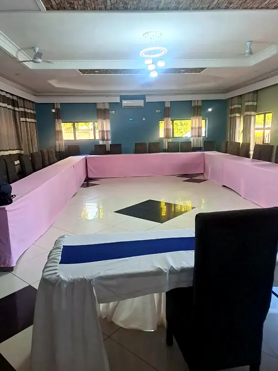The conference hall: tables set in a U, padded chairs, air-con, ceiling fans and a ring chandelier