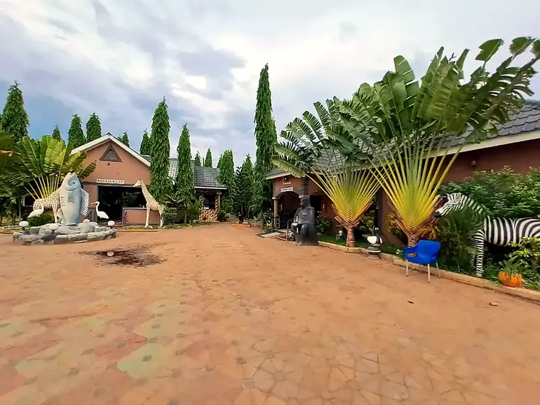 The restaurant across the paved courtyard, with a giraffe sculpture and the fish fountain