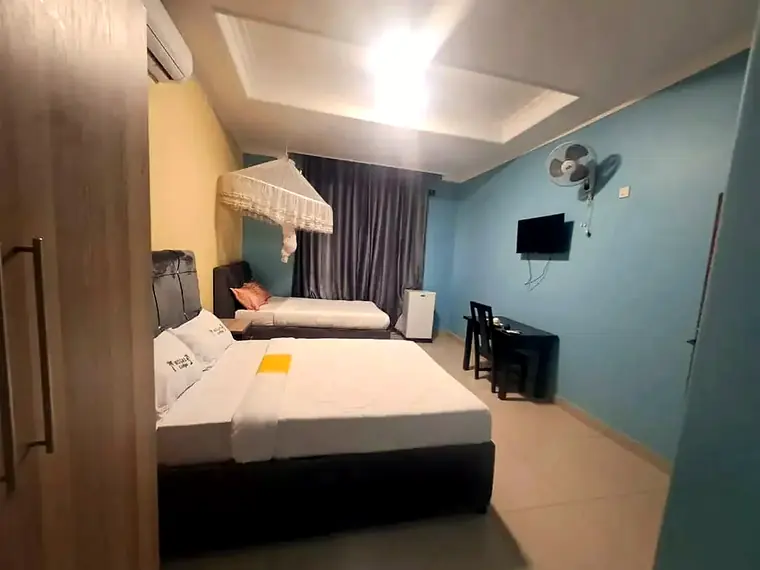 A double bed and a single bed, a fridge, a desk and a wall TV in a blue room